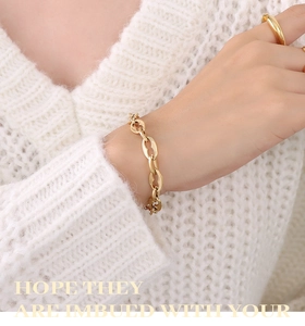 Macro detail of 18K gold plated chain bracelet and minimalist ring on a model