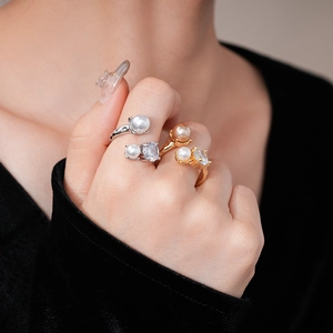 Detail shot of gold and silver open rings with pearls and zircon on model hands