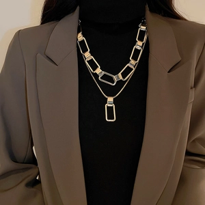 Detail of layered gold chain necklace set with rectangular pendant worn on a model