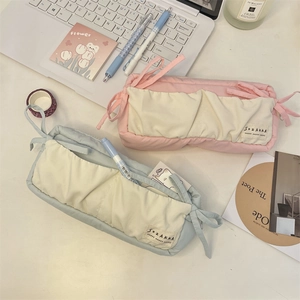 Detail of fabric pencil cases with bow knots and pleated pockets on office desk