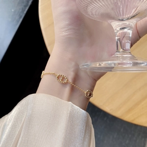 Detail of a minimalist gold hollow ring bracelet on a wrist against a wood background
