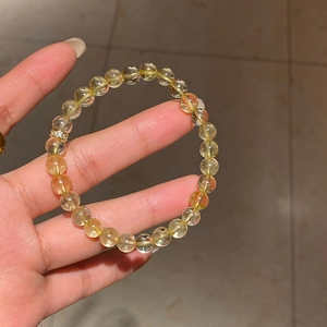 Close-up of yellow citrine bead bracelet featuring a zircon flower metal charm