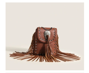 Close-up of bohemian leather handbag with silver studs, skull charm, and long fringe detail