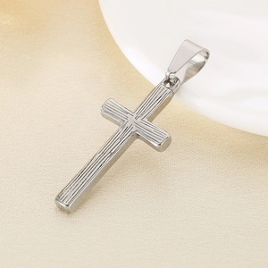 Macro shot of silver cross pendant with vertical stripe texture and smooth metallic finish