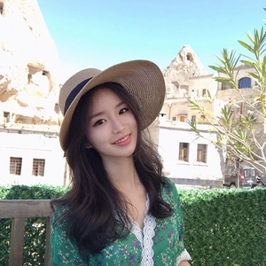 Wide brim straw sun hat with navy ribbon modeled in a bright outdoor summer travel scene