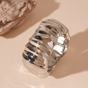 Macro view of wide silver metal cuff featuring intricate industrial pleated textures