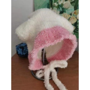 Dettaglio del cappello in peluche crema e rosa con lunghi lacci per le orecchie