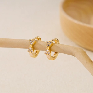 Detail of gold-plated bow earrings with lavender zircon stones hanging on a branch