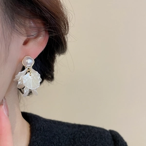Close-up of elegant pearl flower earrings with white resin petals on a model side profile