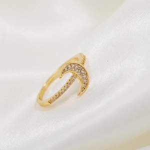 Detailed view of a gold crescent moon ring adorned with shimmering zircon on white silk