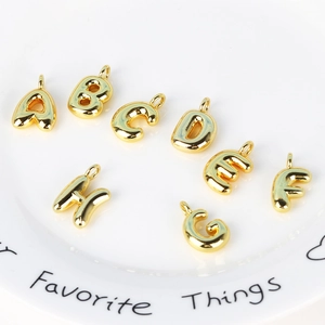 3D gold bubble alphabet pendants A to H on a white plate with metallic finish