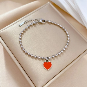 Close-up of titanium steel beaded bracelet featuring a vibrant red enamel heart charm