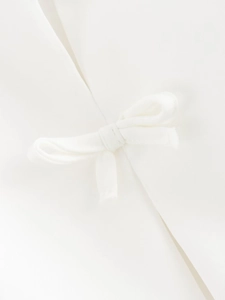 Vista macro dettagliata del top bianco a lupetto con elegante fiocco decorativo
