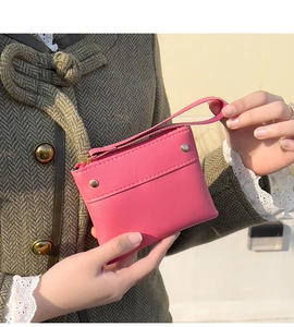 Close-up of pink leather coin purse with gold zipper held against a green wool coat