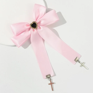 Détail d'un nœud en satin rose avec cœur noir et pendentifs croix en argent stylé