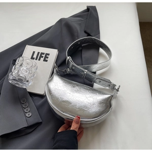 Detailed view of silver crescent dumpling bag with pleated texture and wide strap