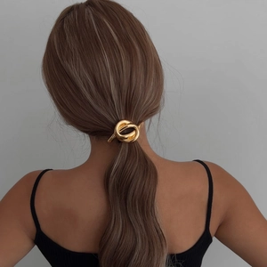 Elegant gold metal bow hair tie with interlocking circular design for a ponytail