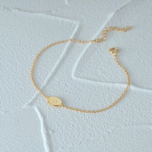 Detail view of a gold oval pendant bracelet with a star diamond and adjustable extension chain