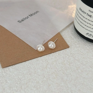 Elegant 925 sterling silver pearl stud earrings shown on a vintage paper background
