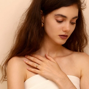 Detail of a vintage 18K gold plated ring featuring a white oval stone and floral diamond halo