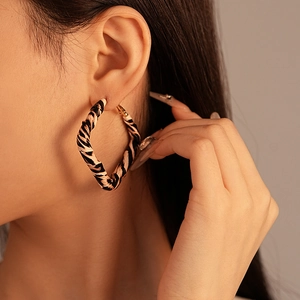 Close-up of model wearing large leopard print faux leather geometric hoop earrings