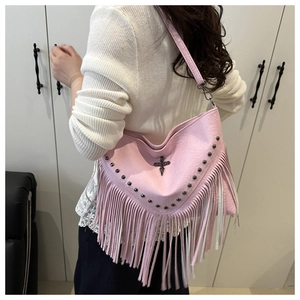 Detail showing pink studded leather crossbody bag with tassels and metallic cross emblem