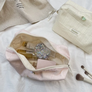 Detailed view of pink and off-white floral makeup bags with lace trim and vertical texture