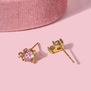 Minimalist round pink zircon stud earrings with gold finish on a soft pink surface