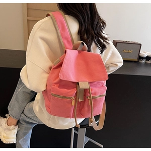 Detalle de la mochila de lona rosa con cordones y cremalleras doradas en una modelo
