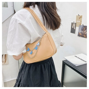 Detail of khaki underarm bag featuring a decorative blue butterfly metal chain strap