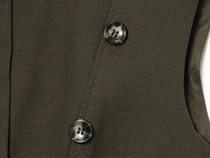 Detail of olive green fabric featuring dark marble buttons and precise stitching