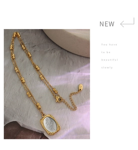 Macro detail of 18K gold plated rose flower pendant with K18 stamp on bead chain