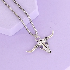 Detailed close-up of a silver bull skull pendant with turquoise and tribal box chain