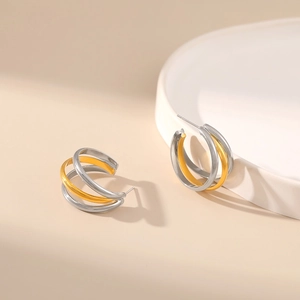 Detailed view of two-tone triple-layer spiral C-shaped earrings on a ceramic tray