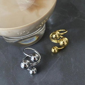 Close-up of gold and silver brass rings with a triple-layer ball design on stone background