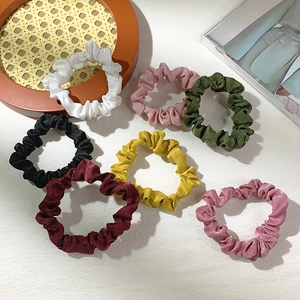 Minimalist velvet scrunchie set in various pastel colors on a textured background