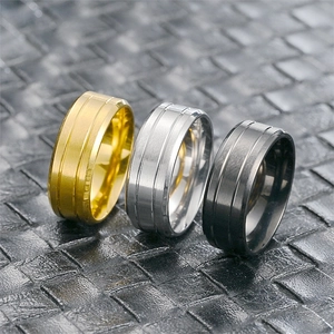 Close-up of matte brushed titanium steel rings with double grooves in gold, silver and black