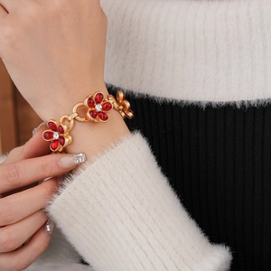Macro shot of vintage style gold bracelet with red flower charms and crystal accents