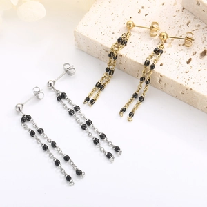 Detail of long gold and silver tassel earrings with delicate black resin beaded accents