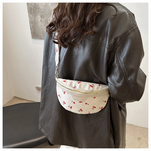 Detailed view of white crossbody bag with red cherry prints and adjustable wide strap