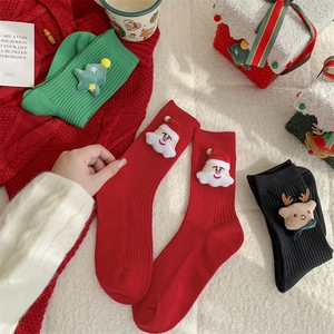 Three pairs of festive Christmas socks with 3D dolls on a cozy white sheepskin rug