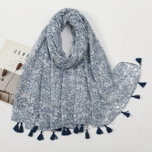 Detail view of navy blue floral scarf with tassels, styled with a magazine and dried plants