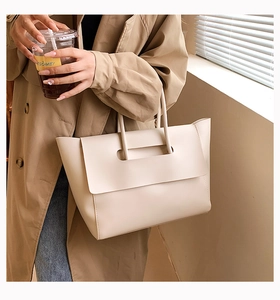 Detail of beige leather commuter handbag showing unique cutout handle and flap design