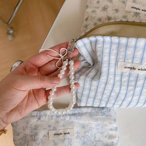 Close-up of elegant pearl handle strap with silver bow charm on blue floral fabric bag
