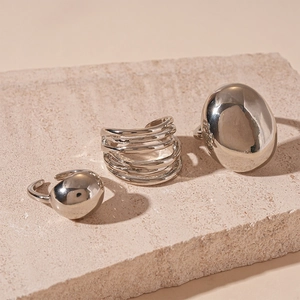 Detailed view of silver minimalist multi-layer and oval rings on white textured stone