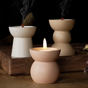 Three minimalist matte ceramic candle holders in muted tones on a vintage wood base