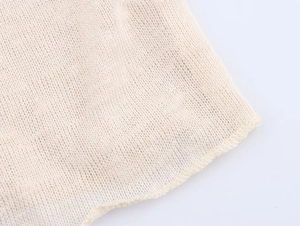 Close-up of beige ruffled knit fabric showing delicate mesh texture and hem detail