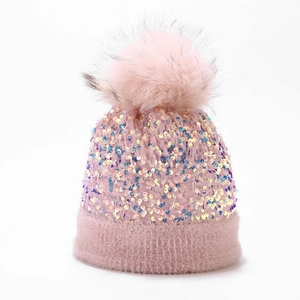 Close-up of pink knit beanie featuring colorful sequins and a large faux fur pom-pom