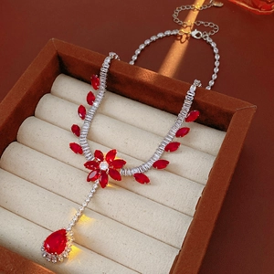 Detailed macro view of a vintage silver flower necklace with red zircon teardrop pendant