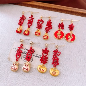 Detailed close-up of festive red and gold Chinese New Year tassel earrings with lucky charms